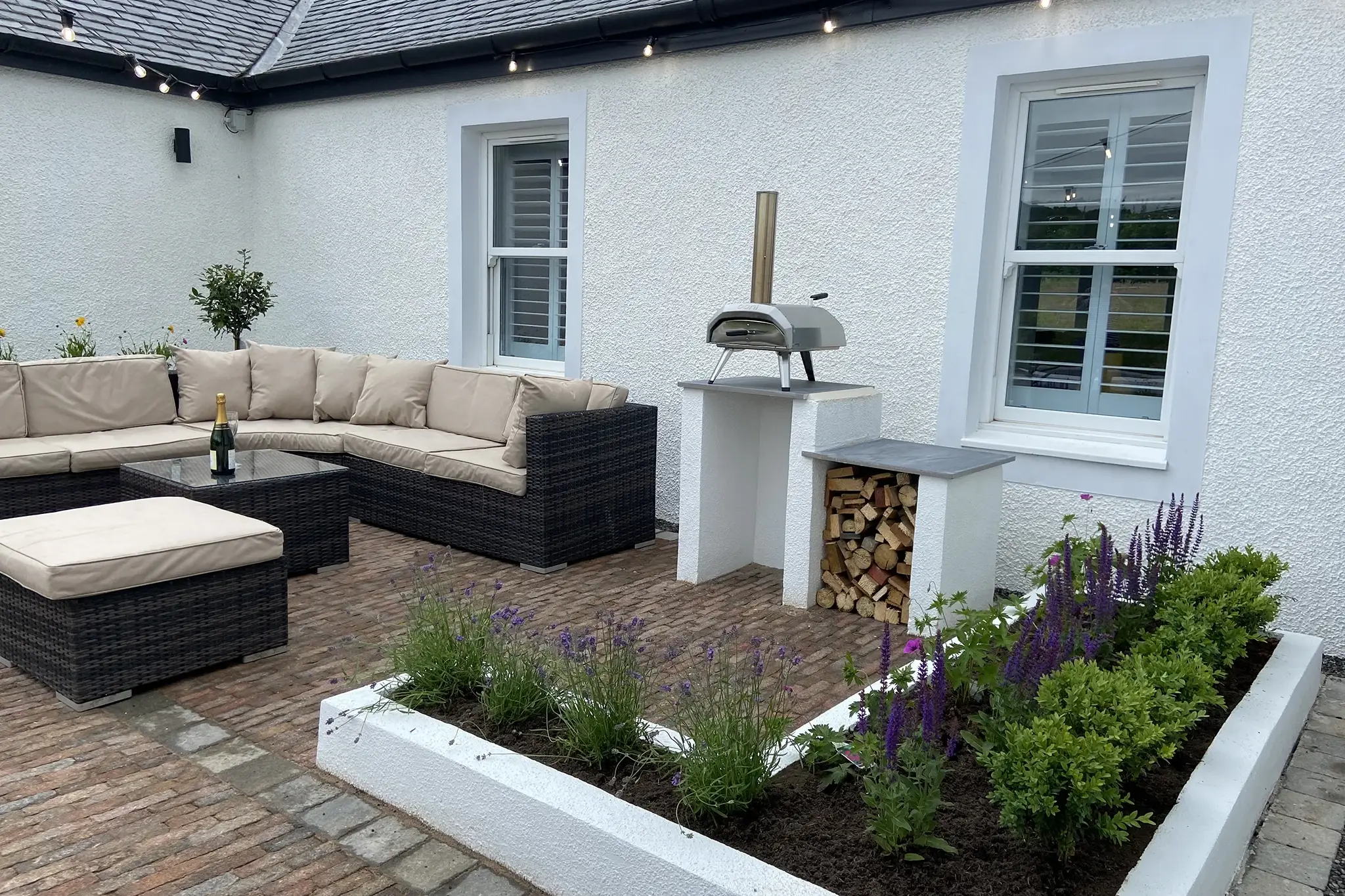 Garden Room Office in Ayrshire: Comfortable All Year Round 9 Courtyard garden with outdoor sofa, raised planters and a pizza oven beside a whitewashed Ayrshire cottage